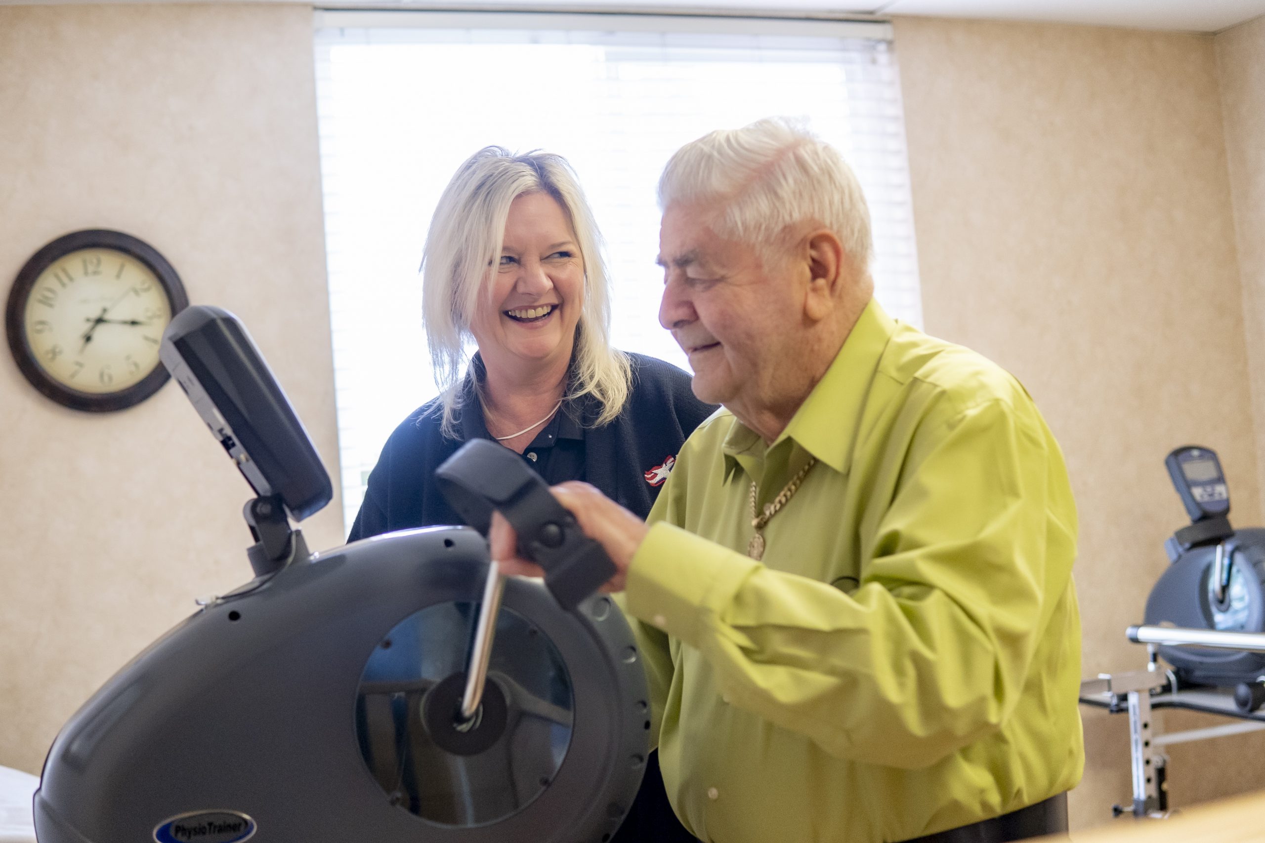 freedom village fitness instructor helping a senior man use an exercise machine